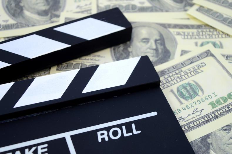 Film clapboard on top of $100 bills