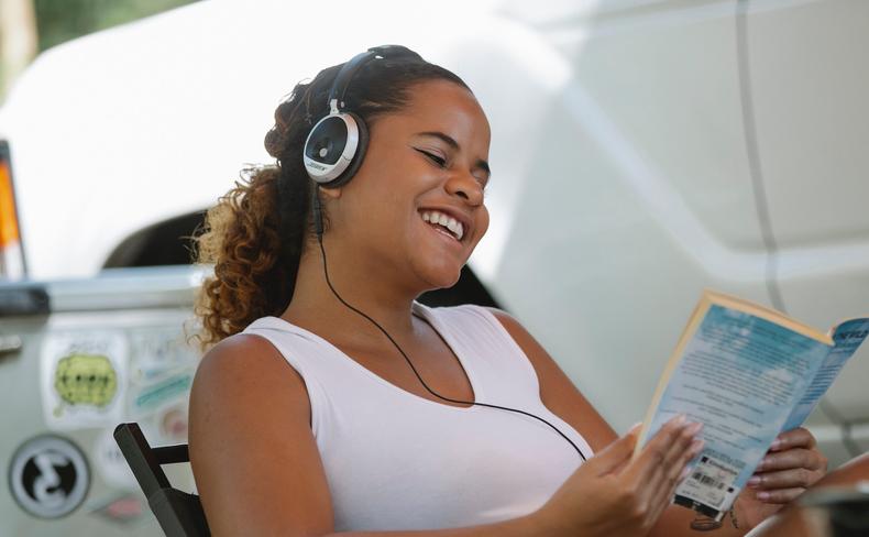 Woman reading a book while wearing headphones
