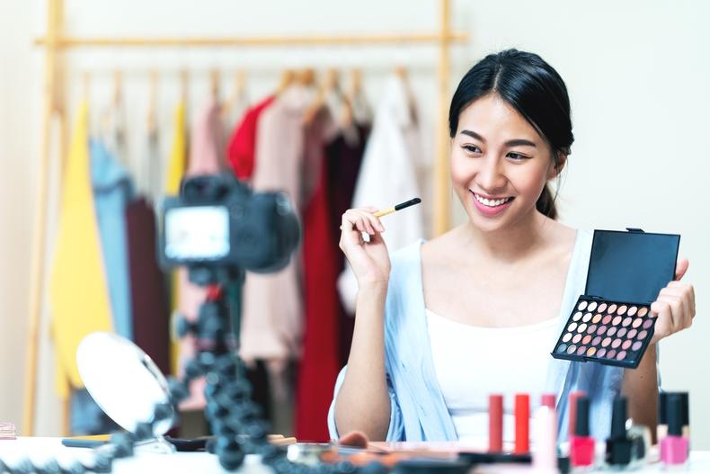 Influencer holding makeup supplies in front of camera