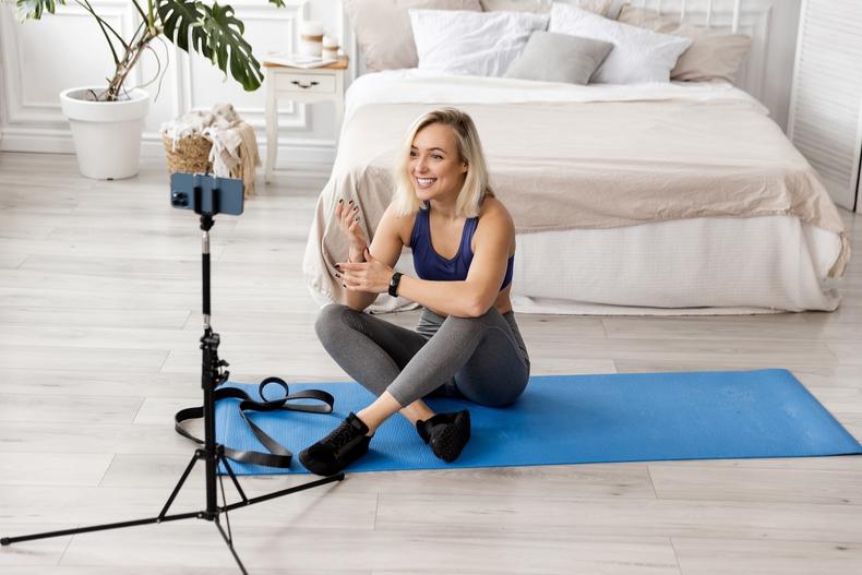Woman recording a fitness video while sitting on a yoga mat