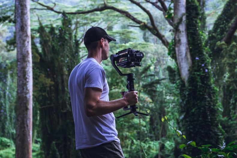 Man using a handheld camera in a forest