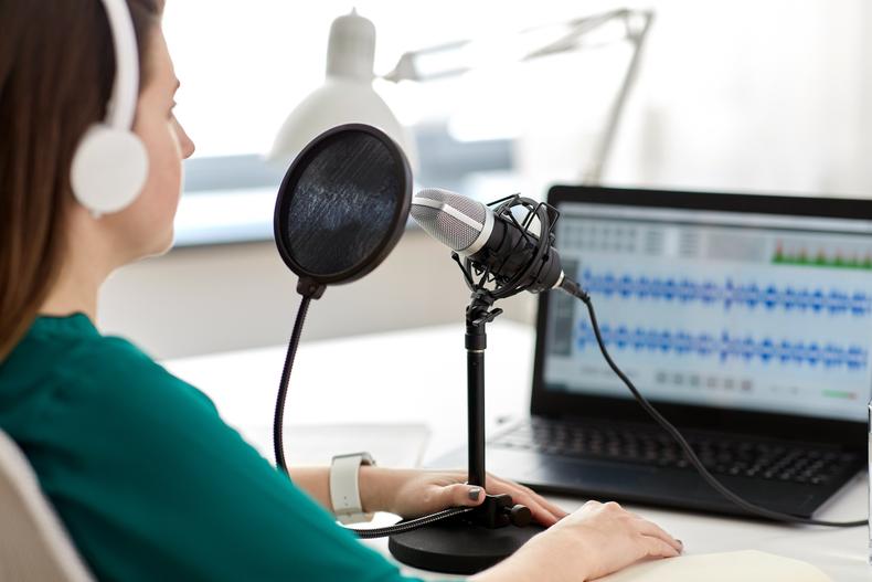 Podcast in front of a microphone and a computer