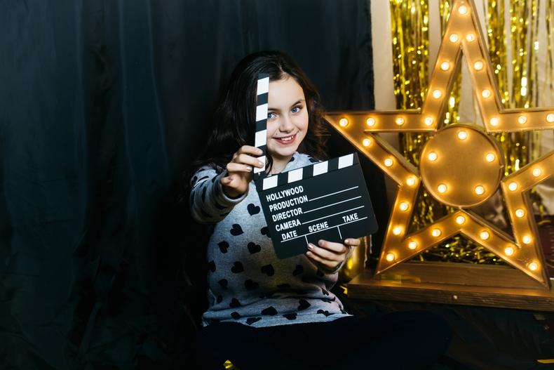 Child actor holding a clapperboard in front of a light-up star