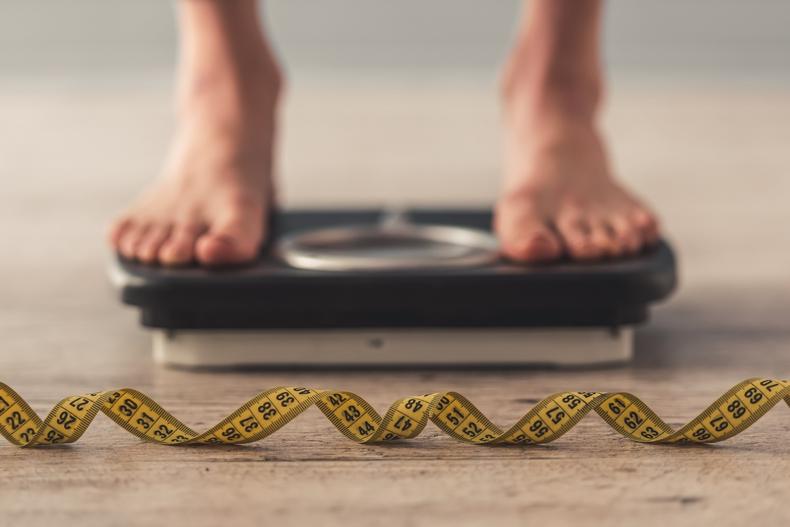 Feet on a scale with a cloth tape measure in the foreground