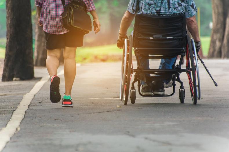 Person walking next to a person in a wheelchair