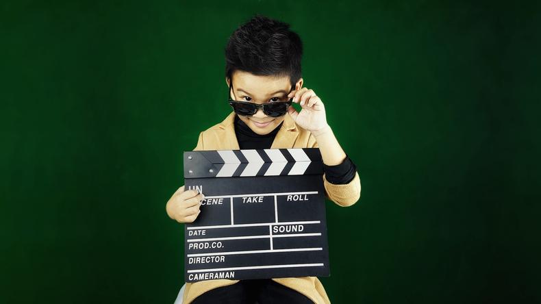 Male child actor holding a clapperboard
