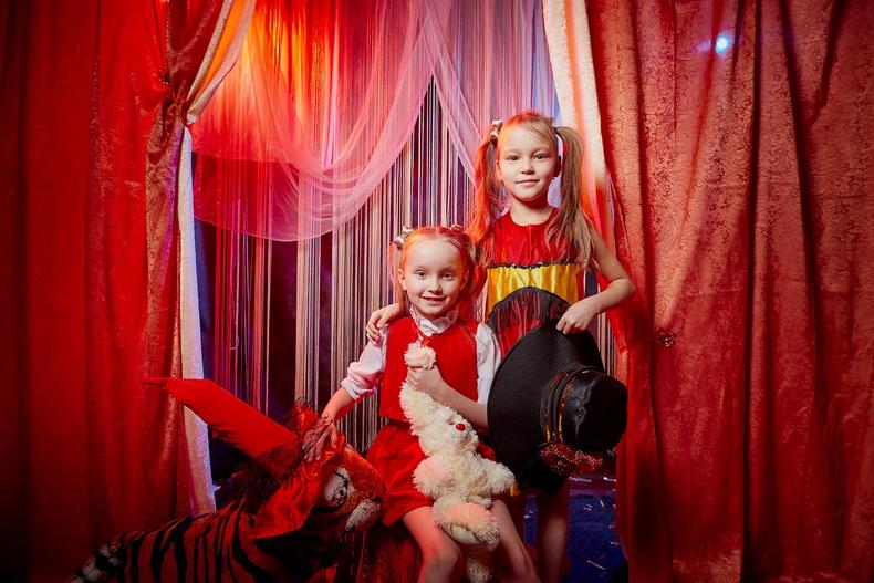 Two female child actors standing in front of a red curtain