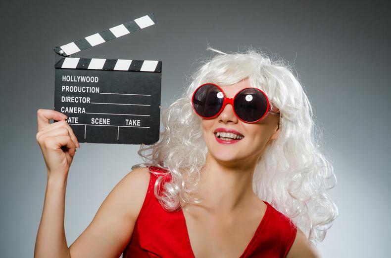 Woman in sunglasses holding a clapperboard